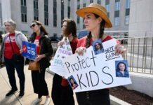 Lauren Giesler holds a sign with photos of her daughters as she joins other activist mothers at a rally at the state Capitol, March 28, 2023, in Nashville, Tennessee, the day after a shooting at a Christian elementary school in the city. (AP Photo/John Amis)